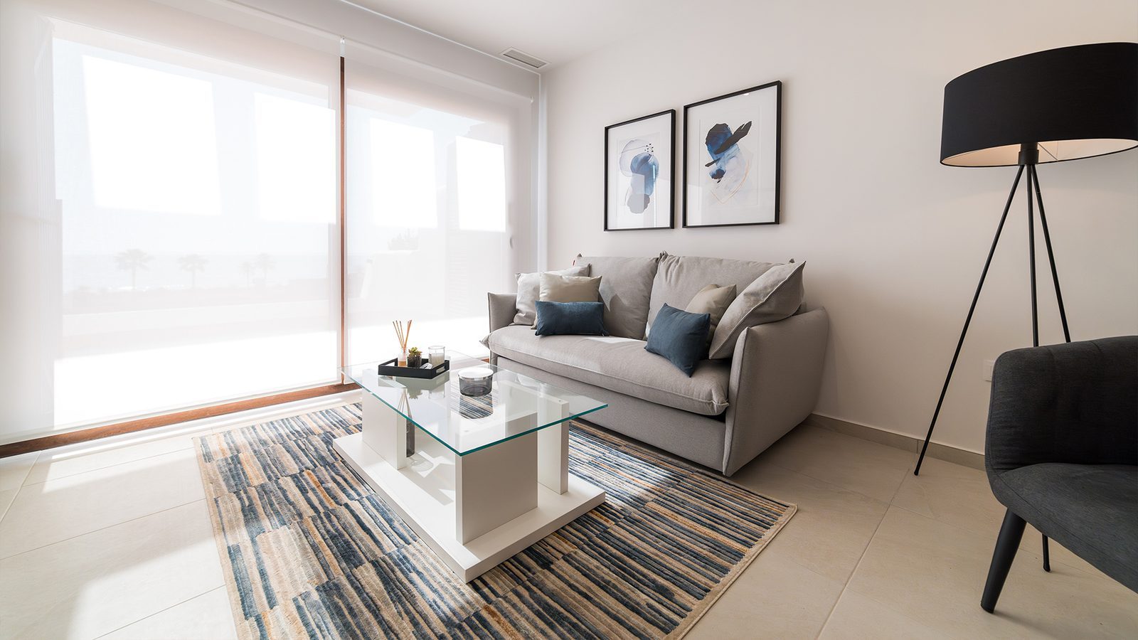 Bright living room with sofa, glass coffee table, patterned rug and sea views through large windows in a 2-bedroom bungalow in Pulpí - The Estates