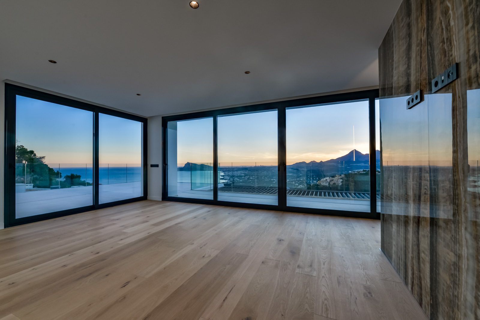 Bright living room with floor-to-ceiling windows and panoramic sea and mountain views of a 4-bedroom