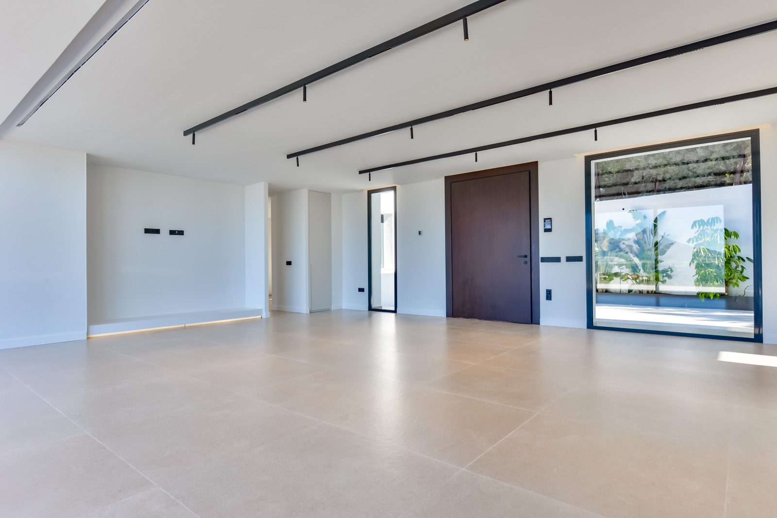 Modern open-plan living room with tiled floors, black ceiling tracks and garden views of a 4-bedroom villa in Altea - The Estates