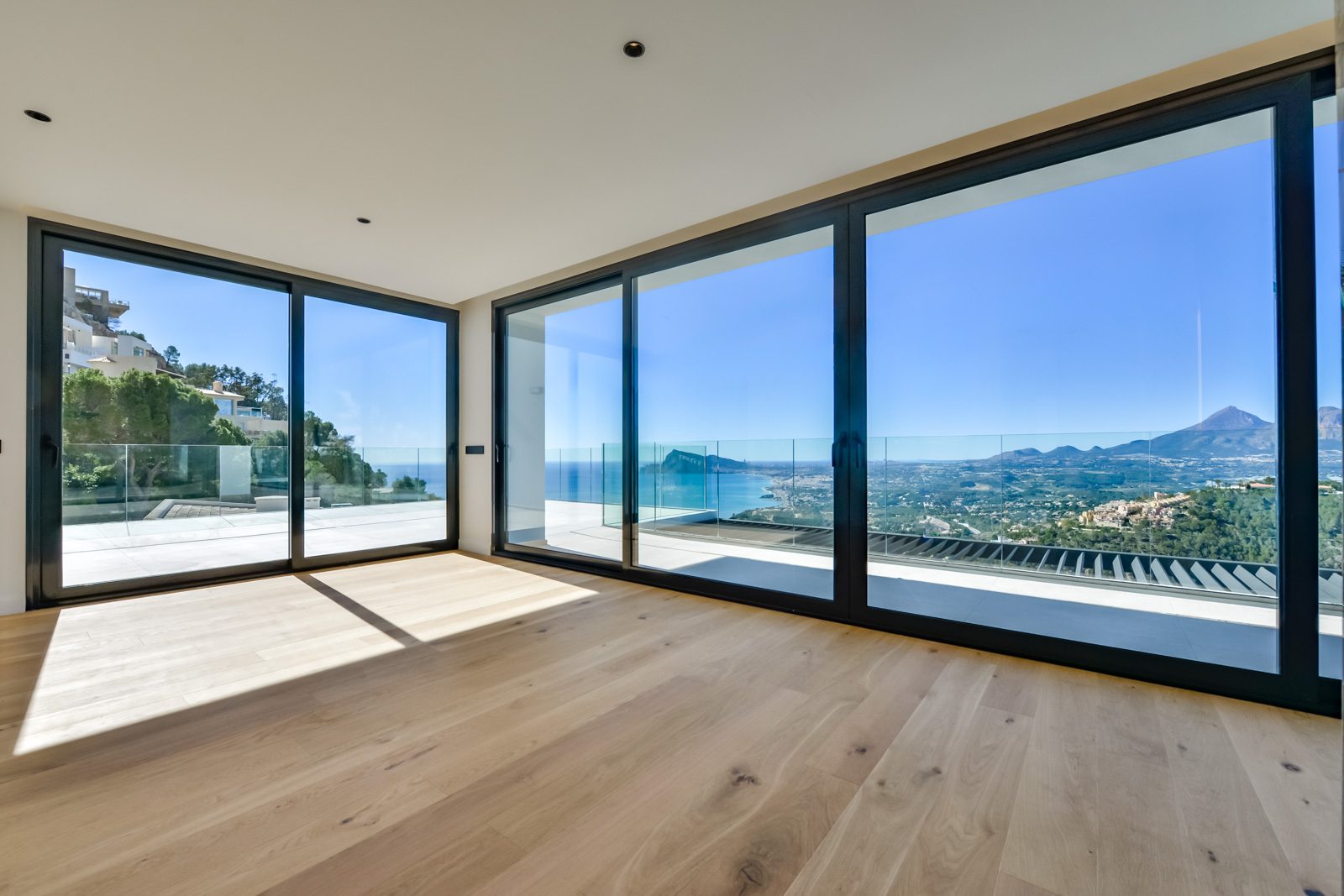Bright interior with floor-to-ceiling windows overlooking panoramic sea and mountain views in Altea Hills, Altea - The Estates