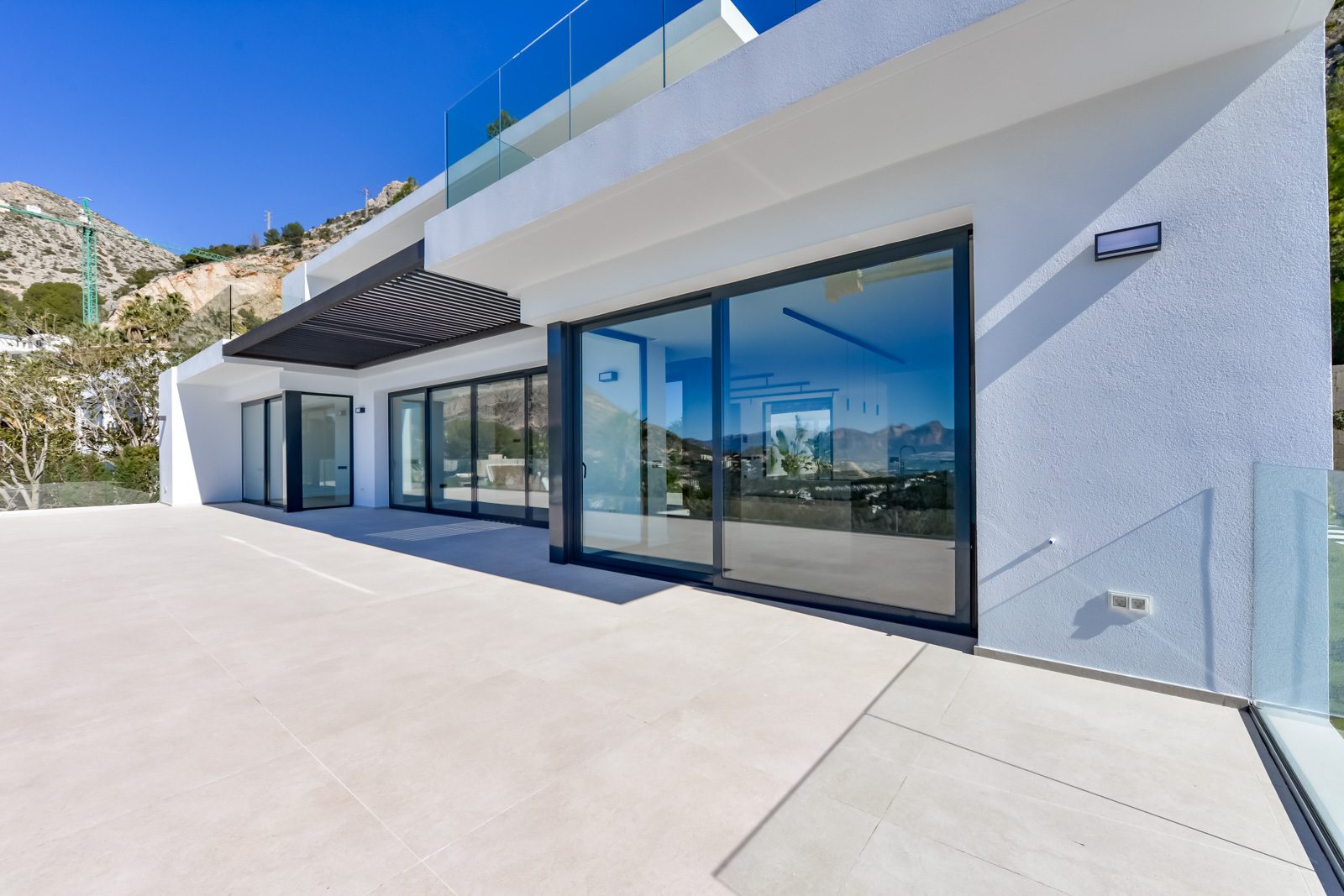 Modern villa terrace with floor-to-ceiling glass doors and mountain views in Altea - The Estates