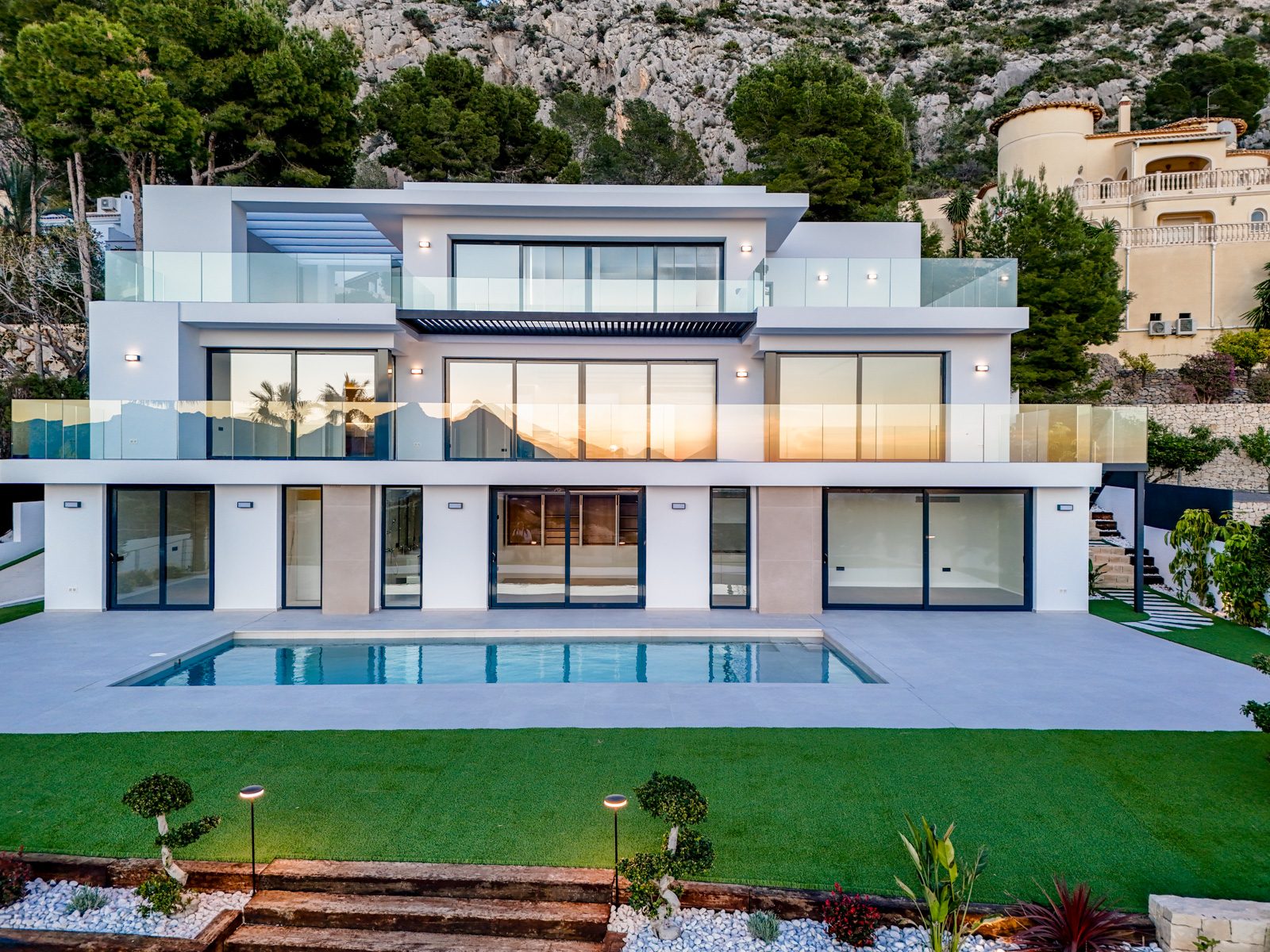 Modern villa with pool, glass terraces and landscaped garden against a mountain backdrop in Altea - The Estates