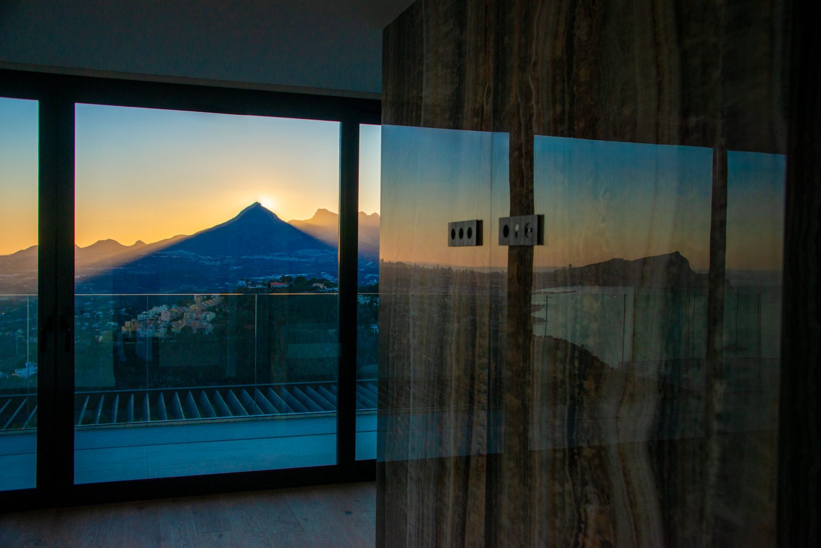 Floor-to-ceiling windows with sunset sea and mountain views inside a 4-bedroom