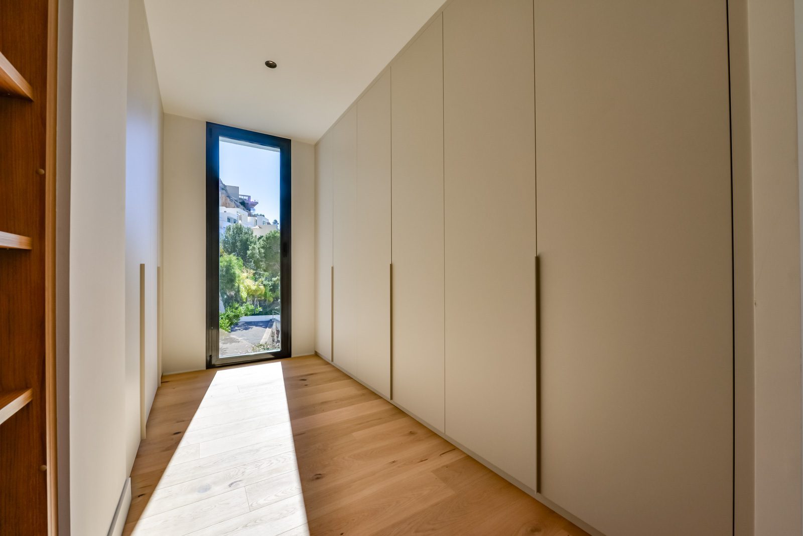 Built-in wardrobes and wooden flooring in a bright dressing room of