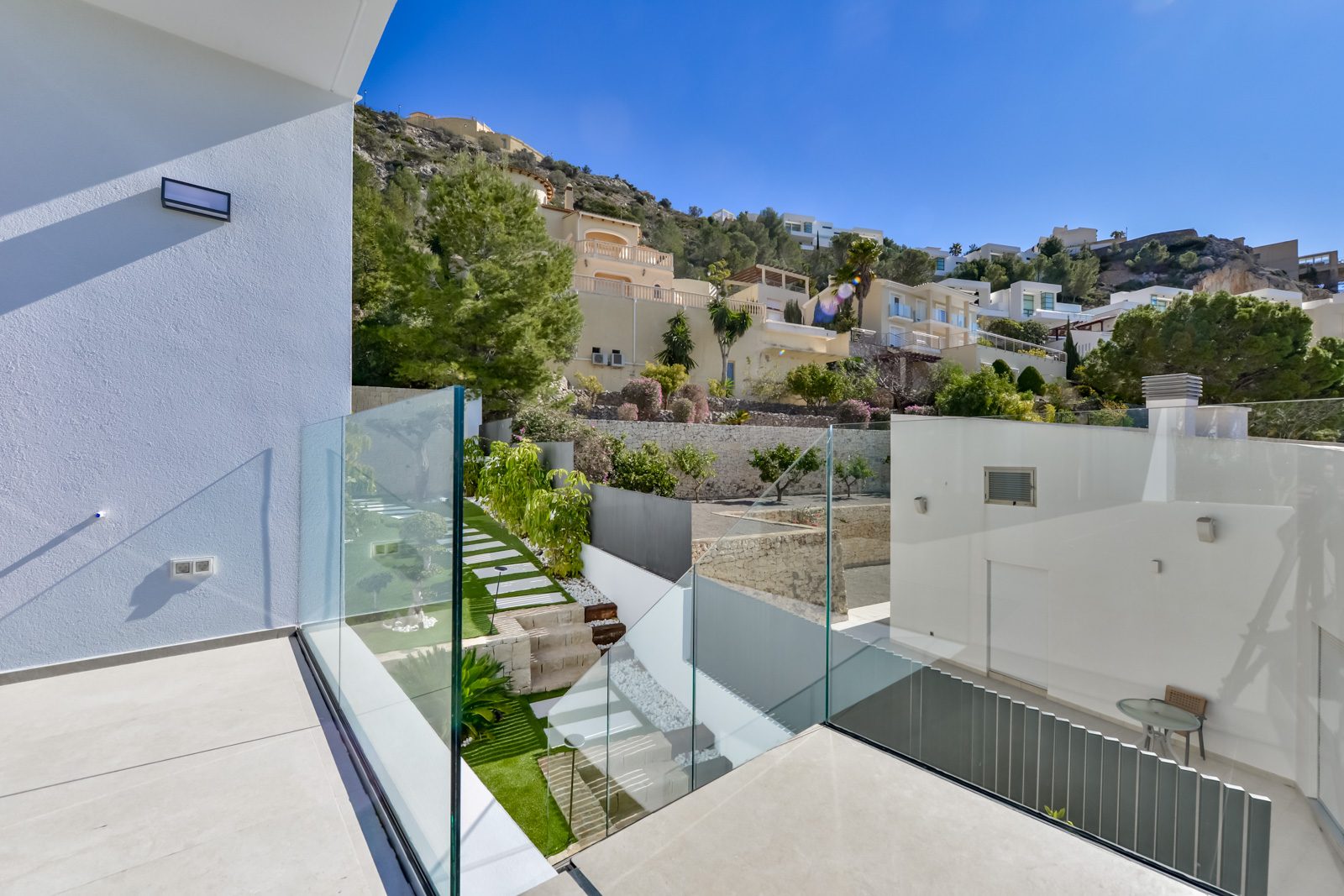 Terrace with glass railings and landscaped garden of a 4-bedroom villa in Altea - The Estates