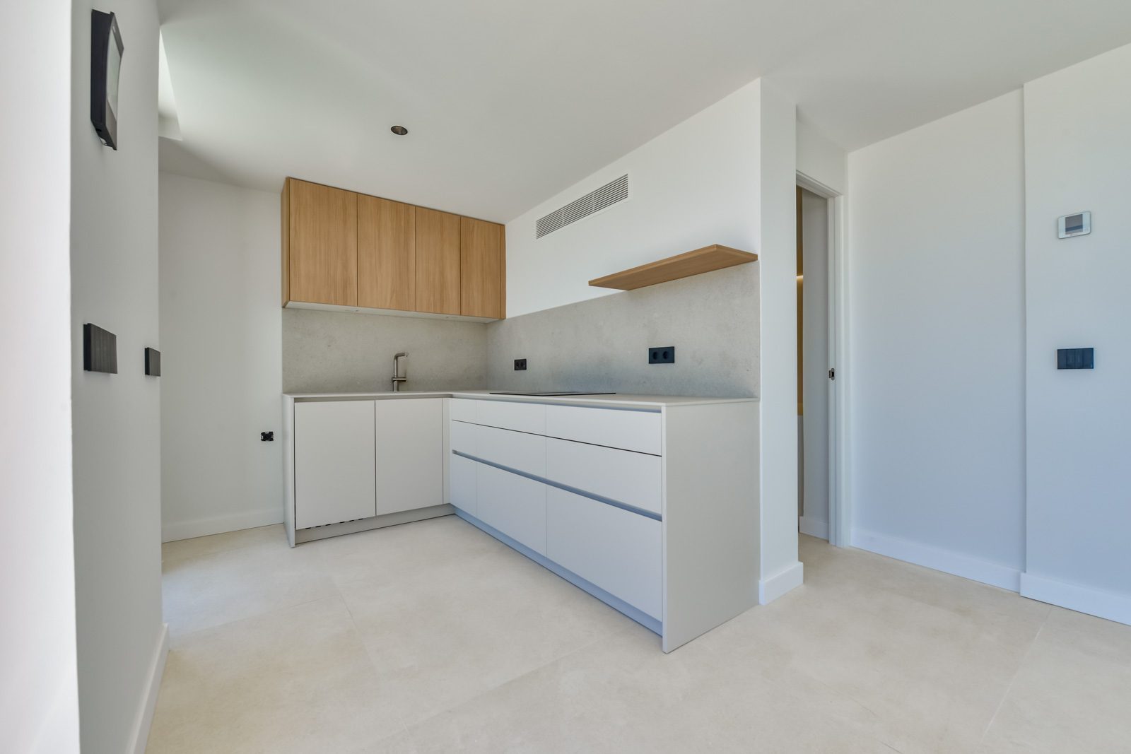 Modern kitchen with white cabinetry, wood accents and concrete-effect backsplash in a 4-bedroom villa in Altea - The Estates