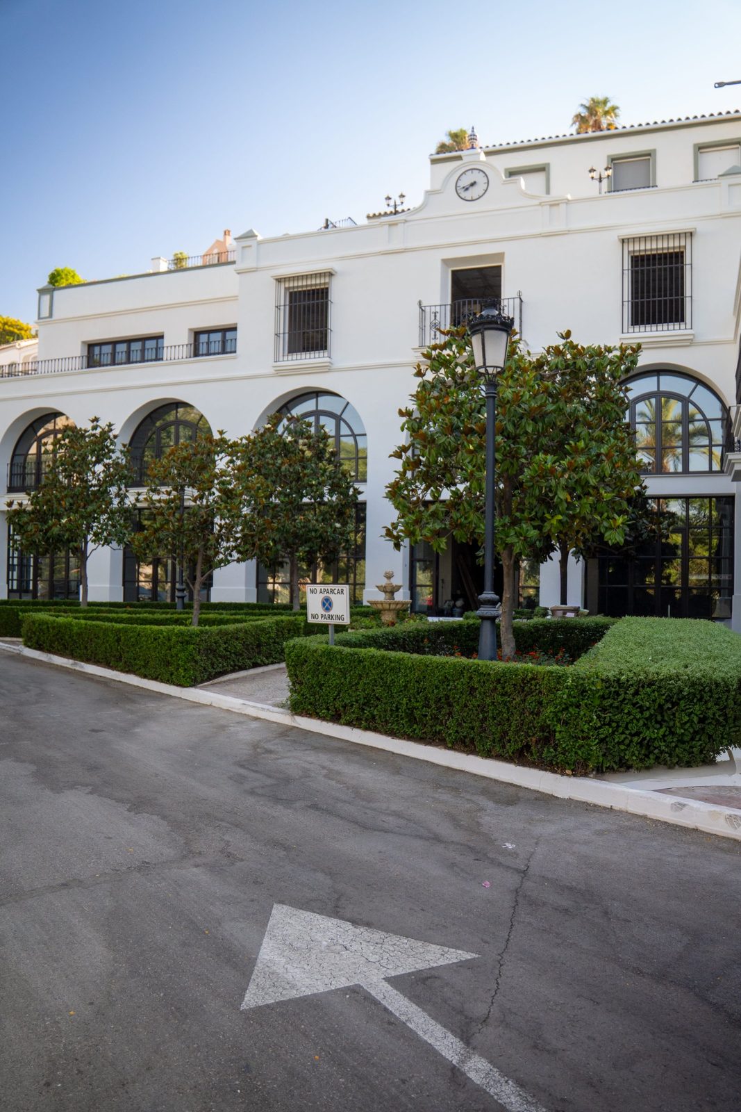 White Mediterranean property exterior with arched windows, clock detail and manicured hedges in Málaga - The Estates