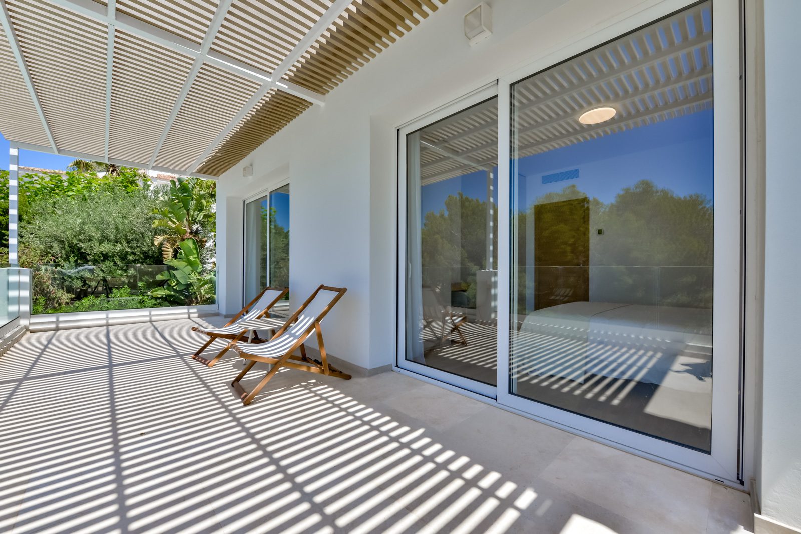 A bright, modern terrace with sliding doors and lounge chairs at a 3-bedroom villa in Altea - The Estates