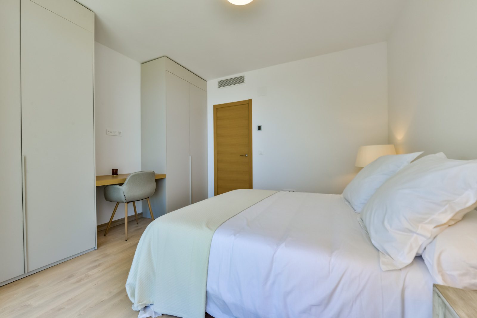 A bright bedroom with built-in wardrobes and a cozy reading nook in a 3-bedroom villa in Altea - The Estates