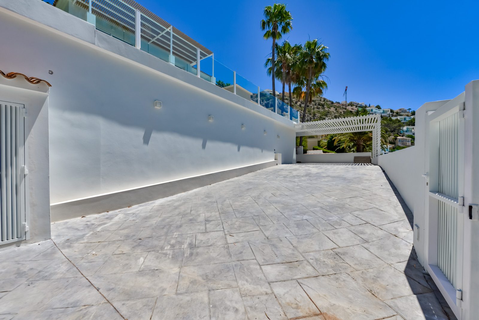 Exterior view of a 3-bedroom villa in Altea, showcasing a paved area and hillside setting - The Estates
