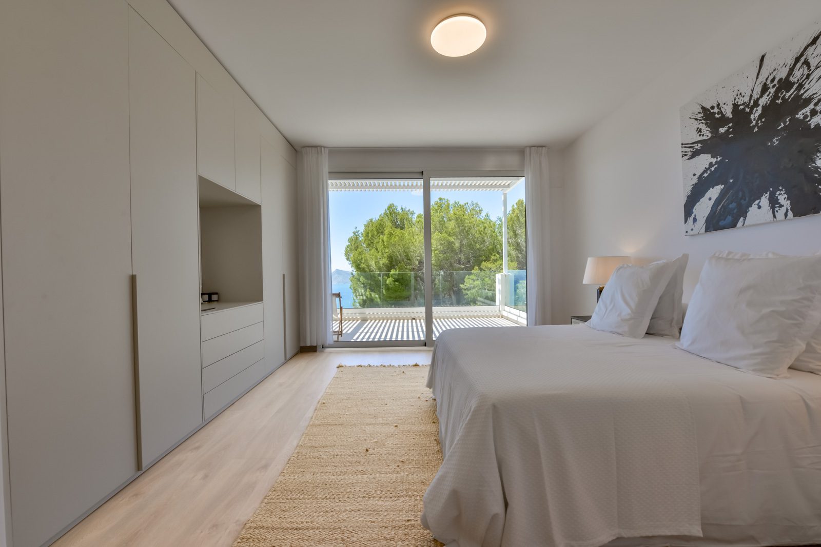 A bright bedroom with built-in wardrobes and sliding doors leading to a terrace in a 3-bedroom villa in Altea - The Estates