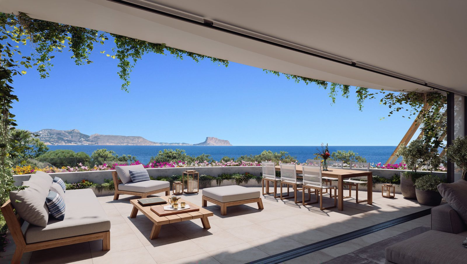 A bright terrace with seating and dining area overlooking sea, garden, and city views of a 3-bedroom apartment in Alfaz del Pi - The Estates