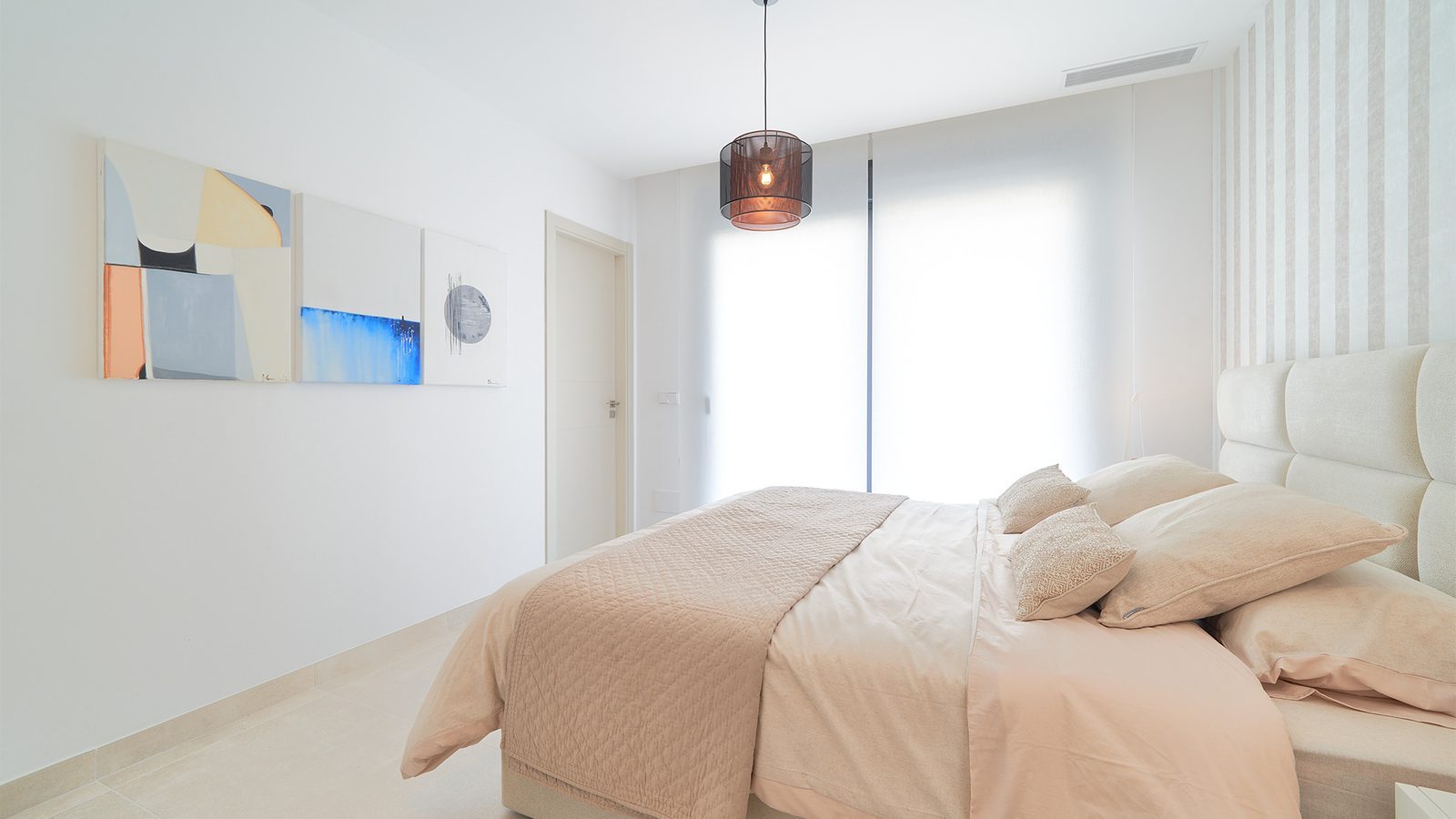 Bright modern bedroom with upholstered headboard, soft bedding, abstract artwork and pendant light in a 3-bedroom apartment in Estepona - The Estates