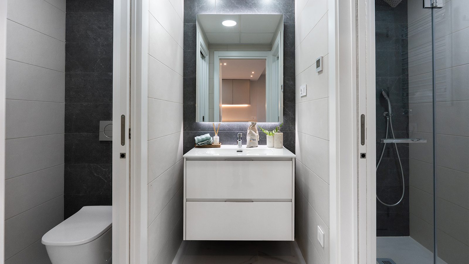 Modern bathroom with vanity, mirror, toilet and walk-in shower in a 2-bedroom apartment in Torrevieja - The Estates