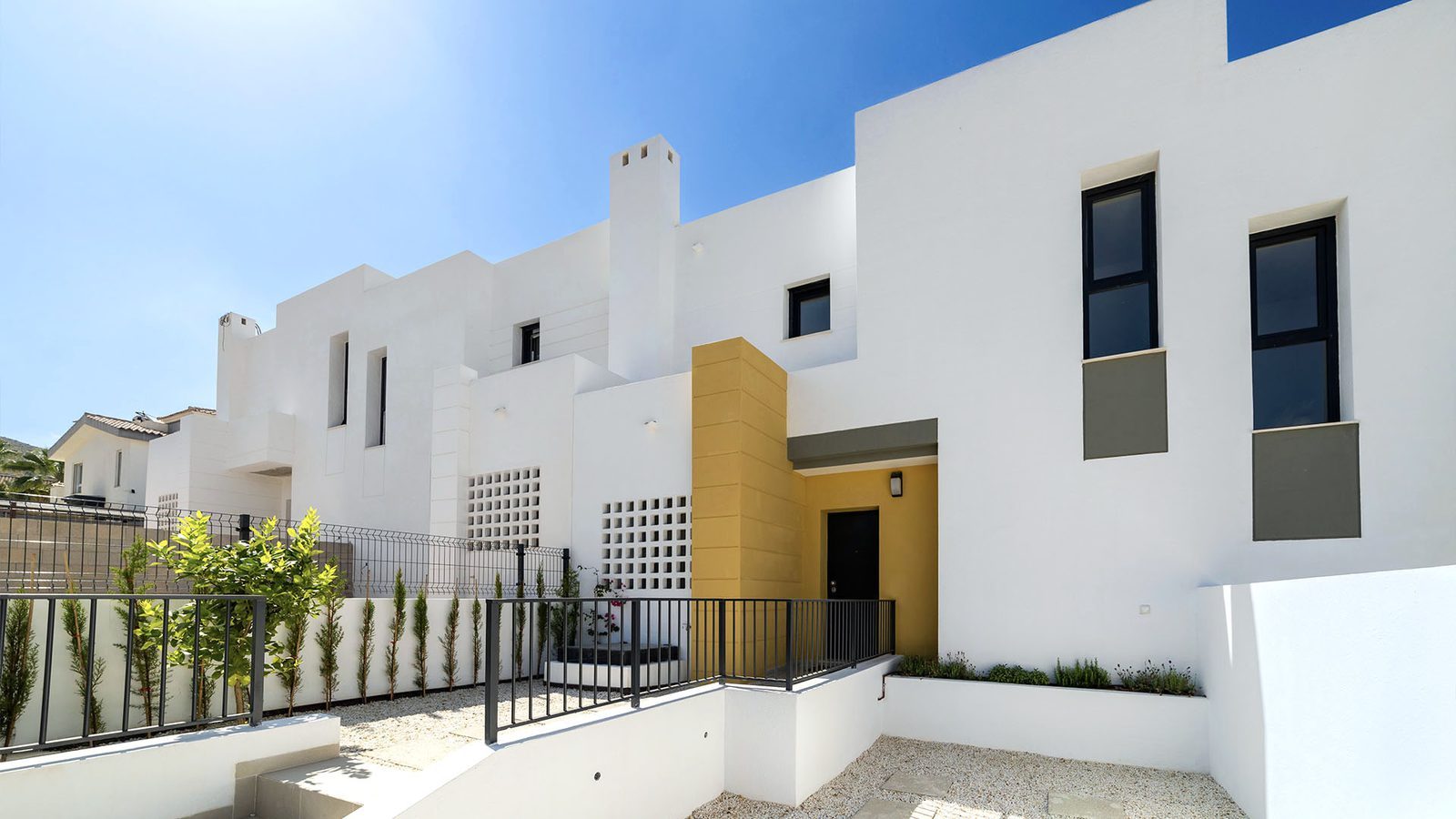 Modern white villa facade with private entrance, terraces and landscaped gravel garden of a 3-bedroom villa in Busot, zona Bonalba Golf - The Estates