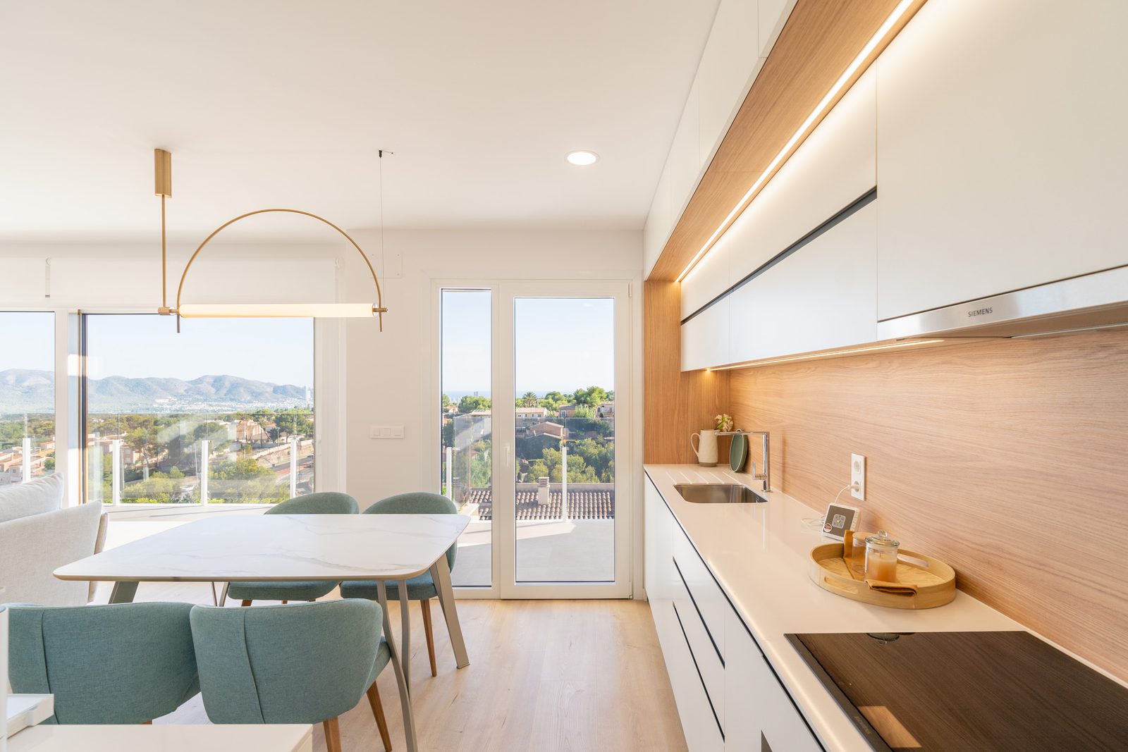A modern kitchen and dining area with stunning sea and city views in a 4-bedroom townhouse in La Nucía - The Estates