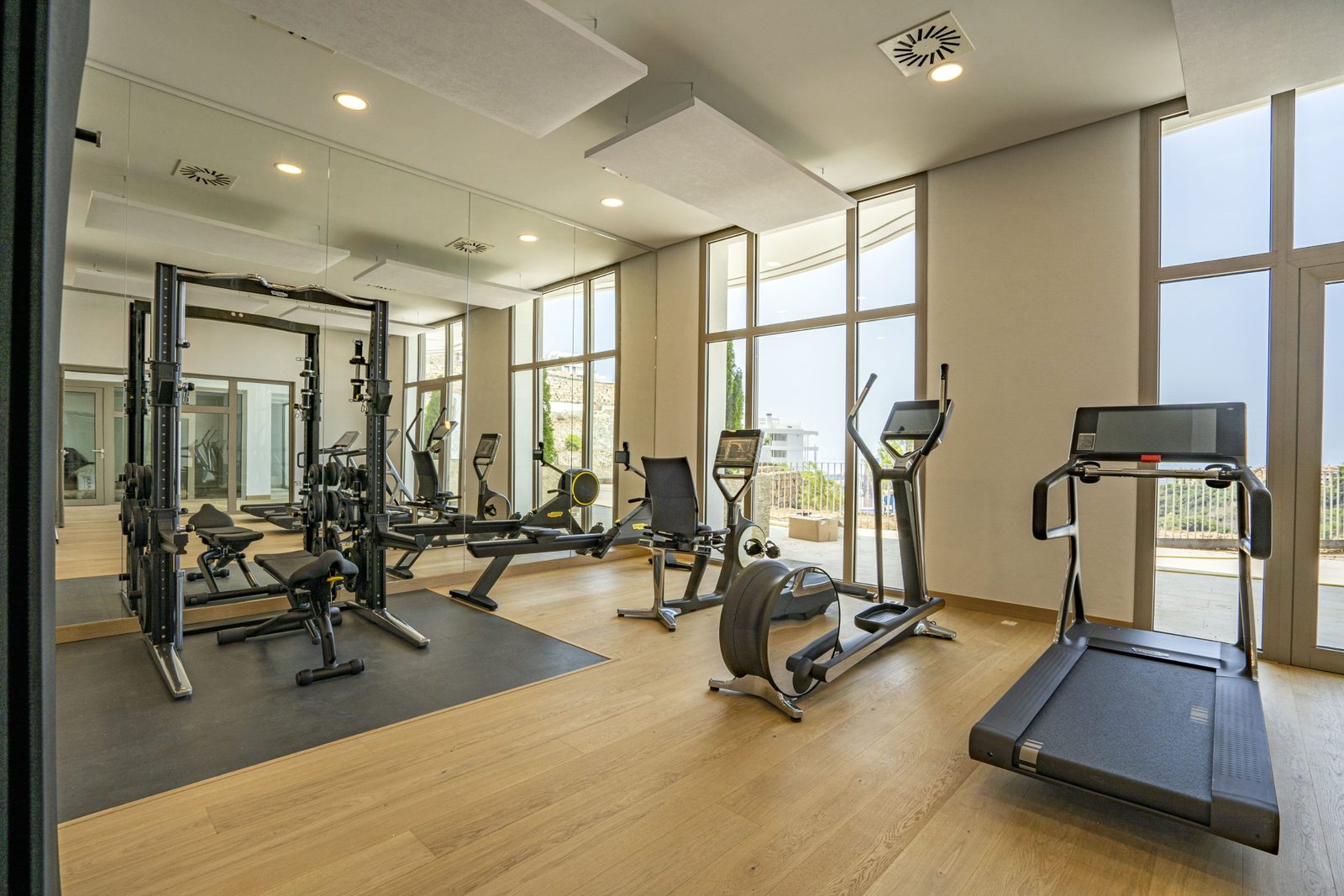 Modern gym with mirrored walls, cardio machines and weights in a 4-bedroom penthouse in Málaga - The Estates