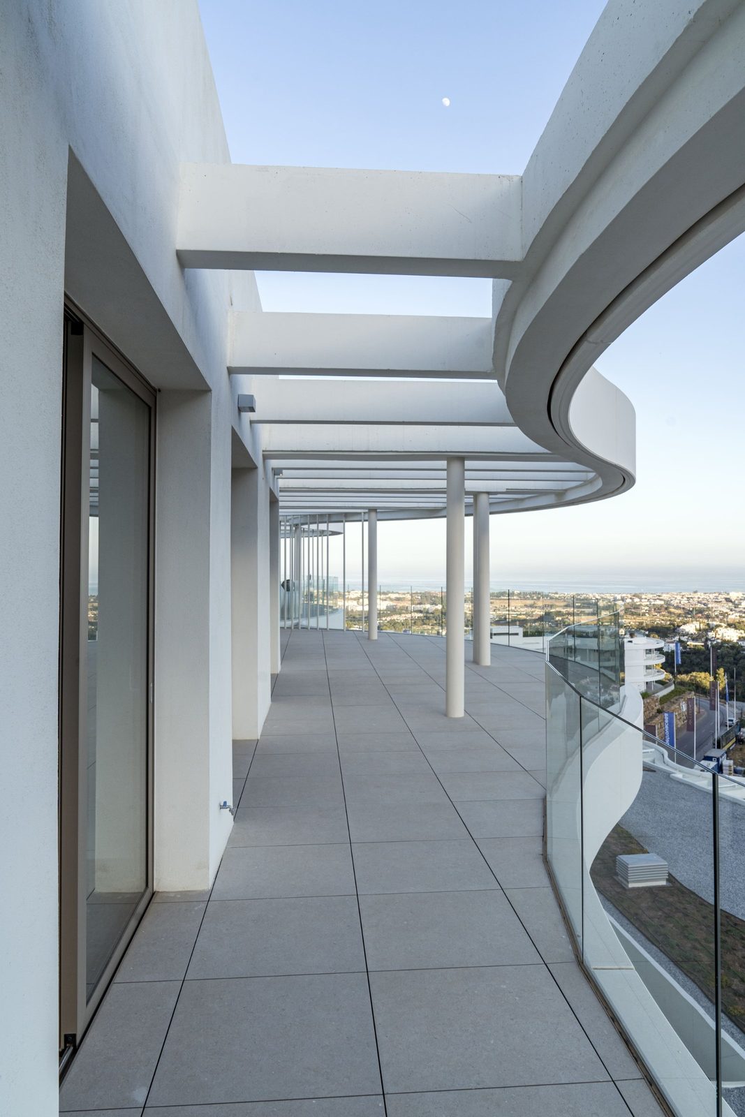 Curved covered terrace with glass railings and sea views of