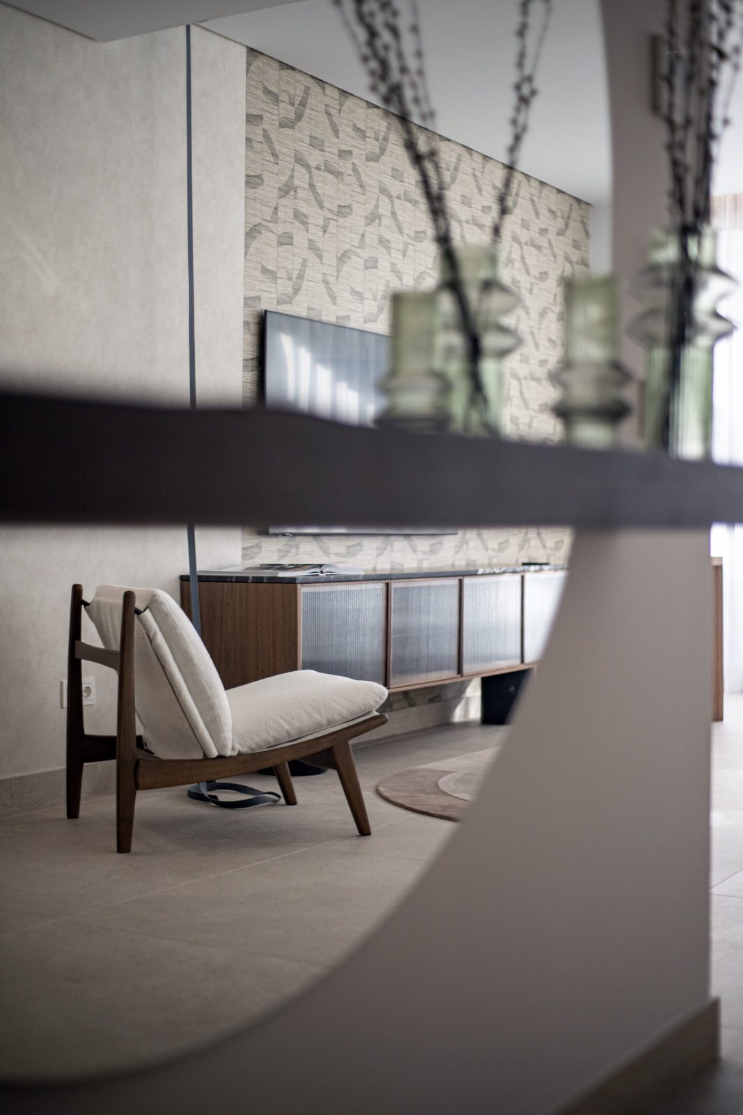 Contemporary living room with an upholstered armchair, textured feature wall, TV and sideboard in a 4-bedroom penthouse in Málaga - The Estates