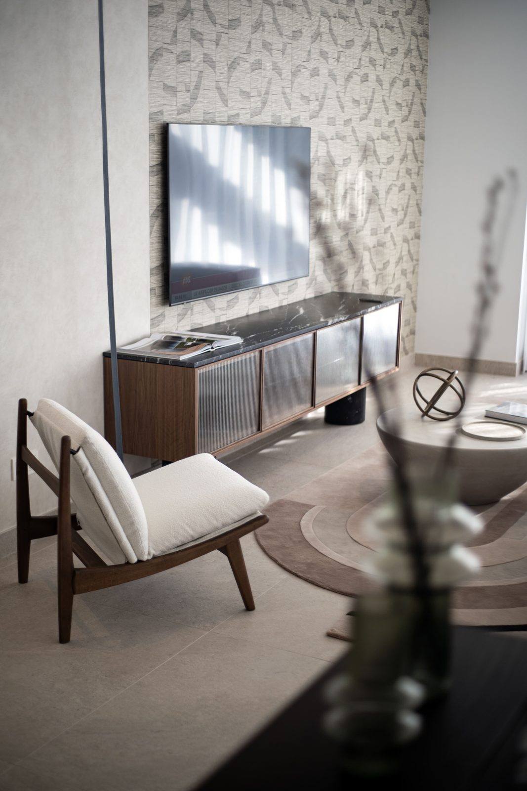 Modern living room with wall-mounted TV, designer chair and coffee table of a 4-bedroom penthouse in Málaga - The Estates