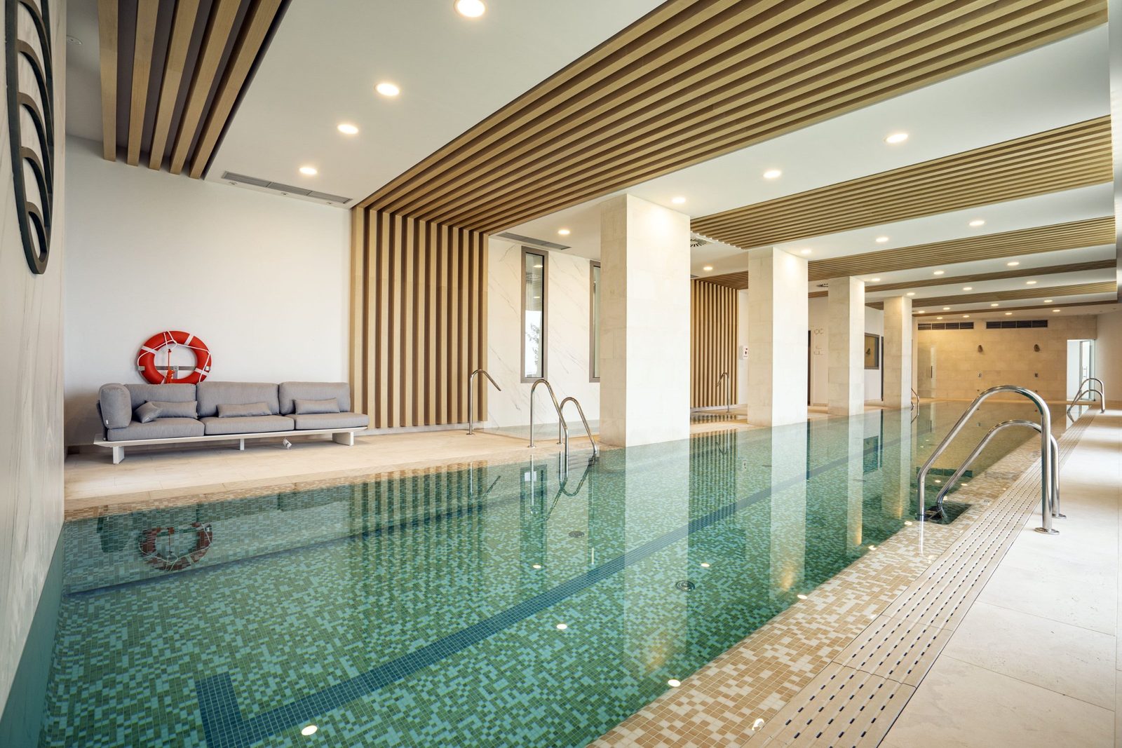 Indoor swimming pool with mosaic tiles and wood-slat ceiling
