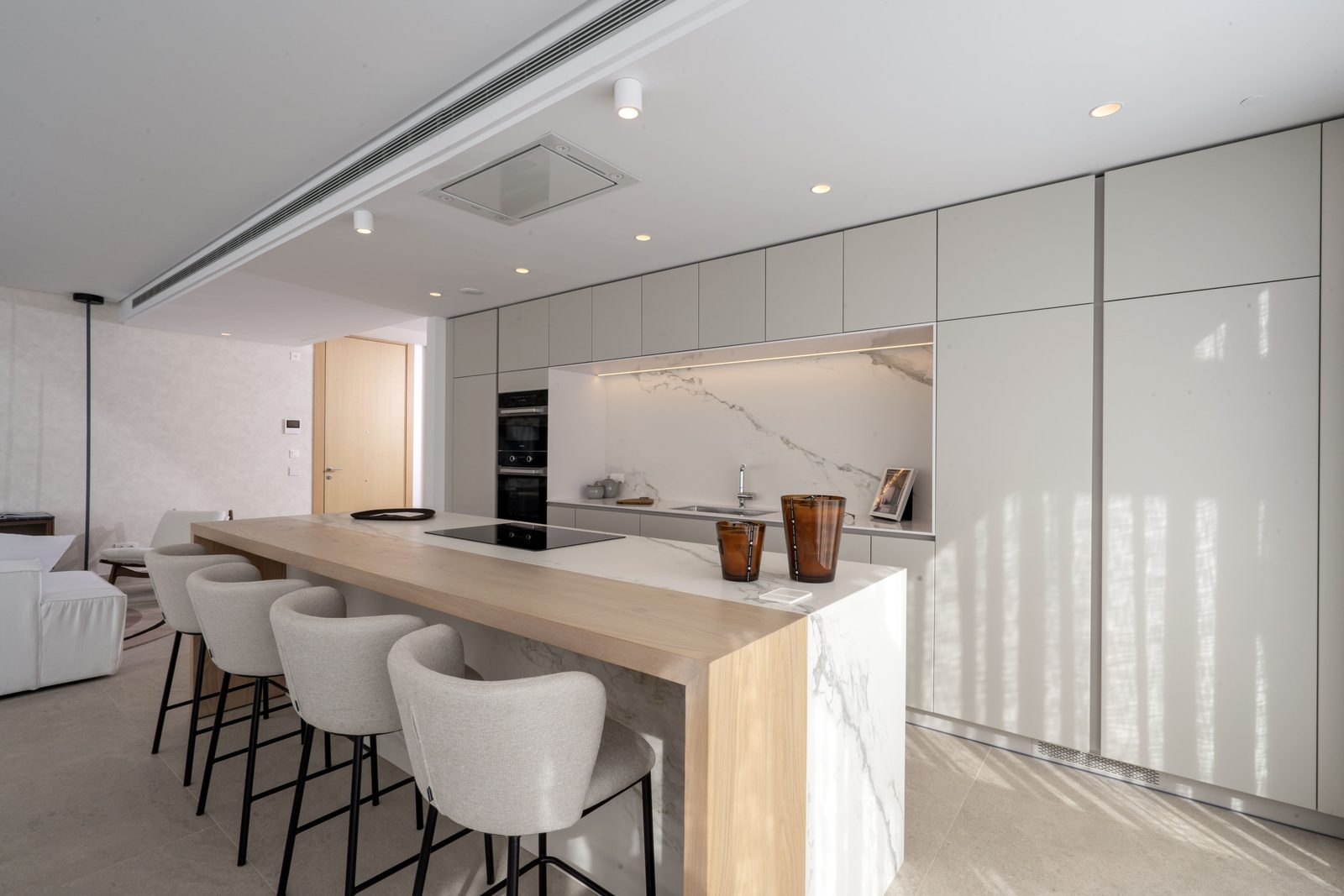 Modern kitchen with marble island and bar seating in a 4-bedroom penthouse in Málaga - The Estates