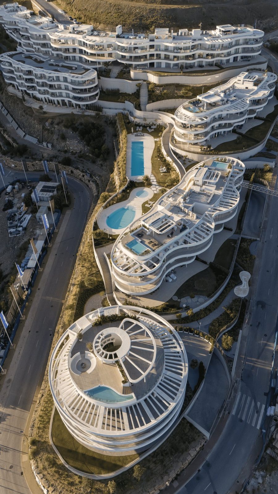 Aerial view of a modern residential complex with rooftop terraces and pools, showcasing sea views, of a 4-bedroom penthouse in Málaga - The Estates