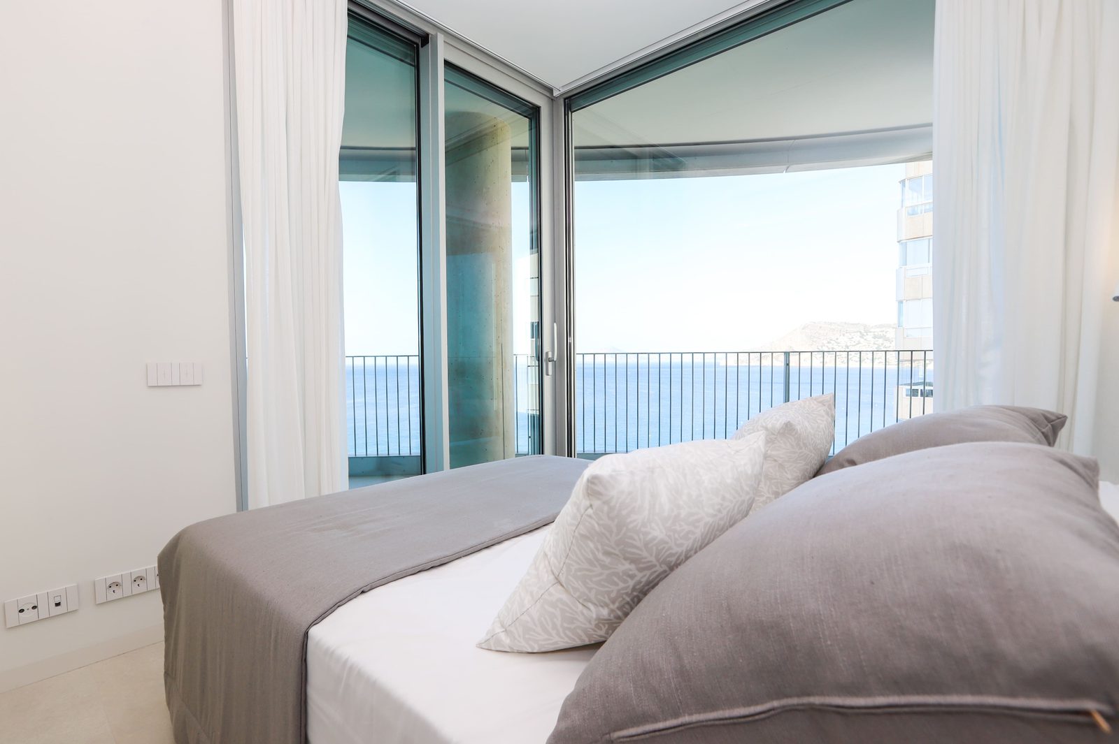 A bedroom with a sea view through large windows in a 4-bedroom apartment in Calpe - The Estates