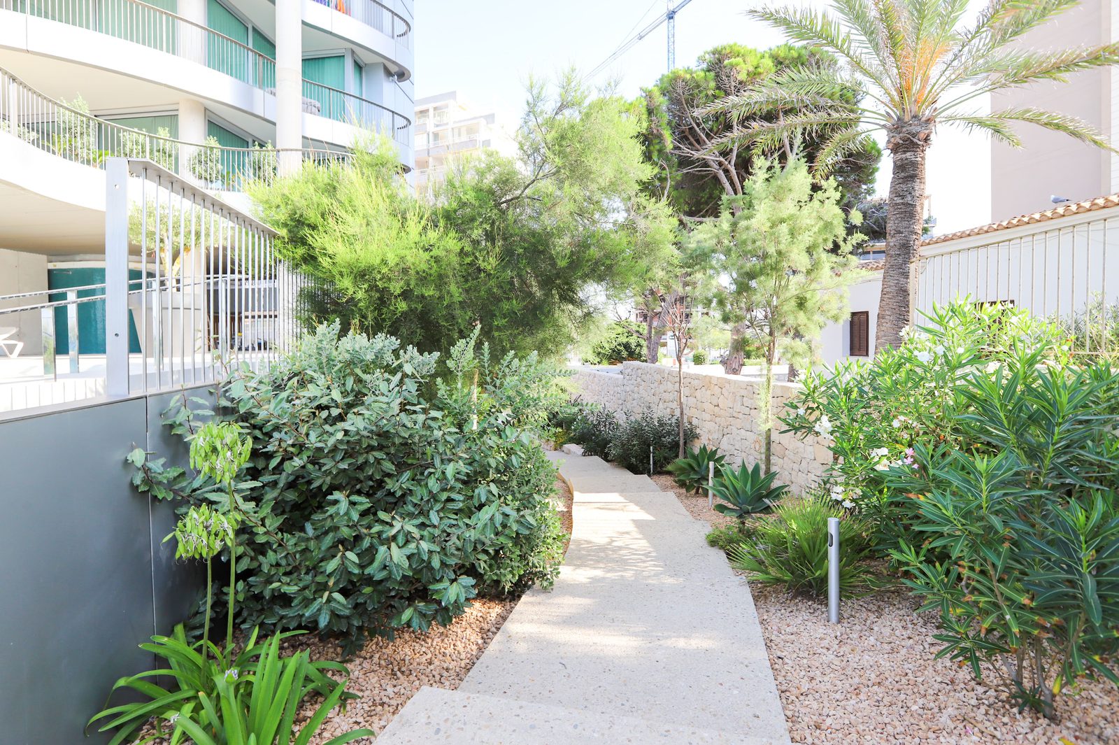 Lush garden path and building exterior of a 4-bedroom apartment in Calpe - The Estates