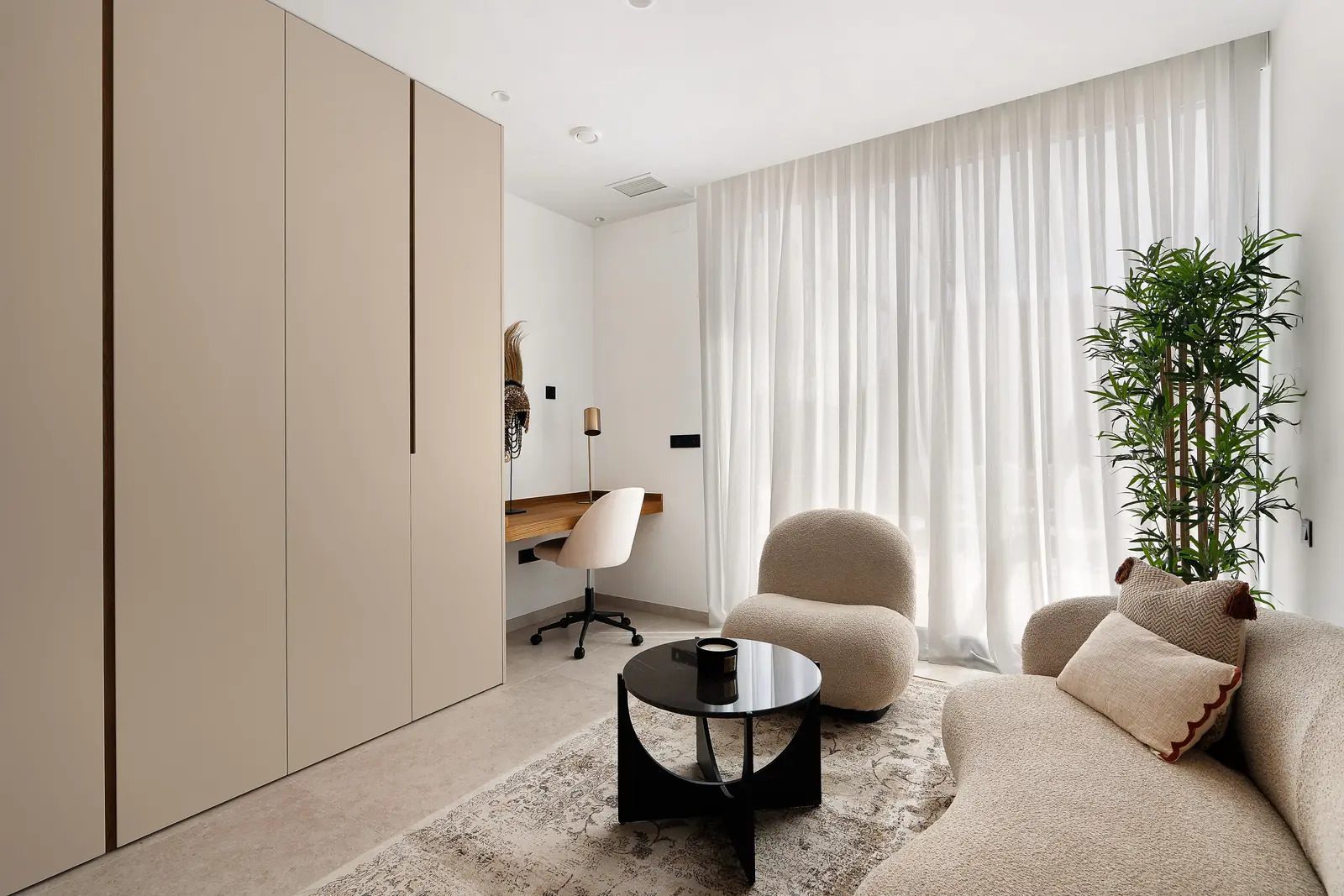 Stylish bedroom with built-in wardrobes, seating area, and plant in a 4-bedroom villa in La Nucia - The Estates