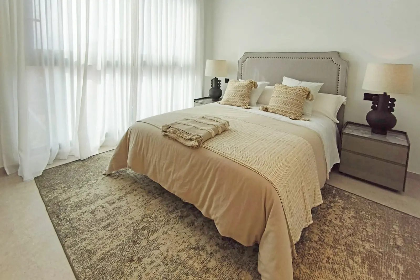 A stylish bedroom with sheer curtains and a comfortable bed in a 4-bedroom villa in La Nucia - The Estates