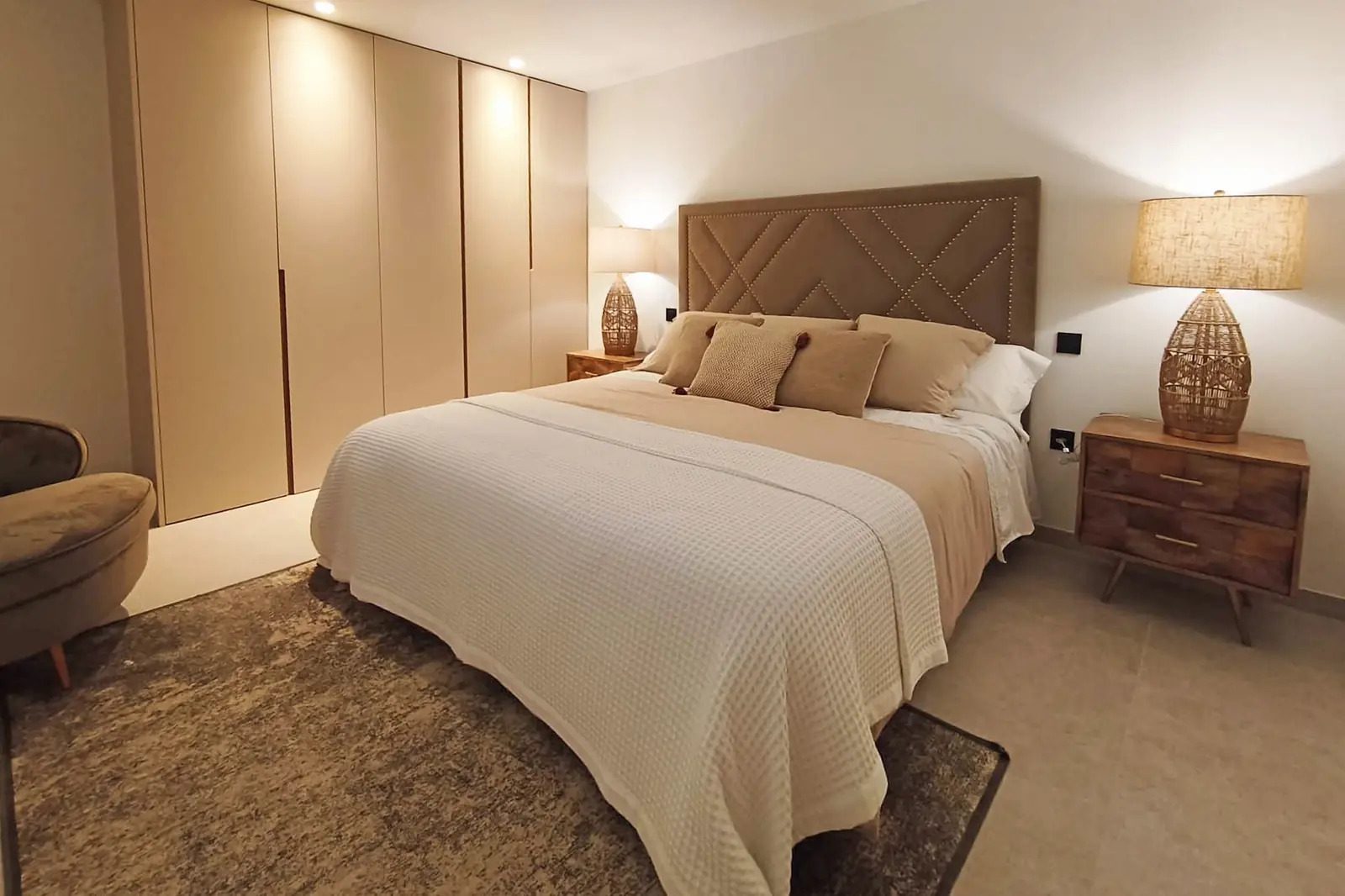 A stylish bedroom with a large bed and bedside tables in a 4-bedroom villa in La Nucia - The Estates