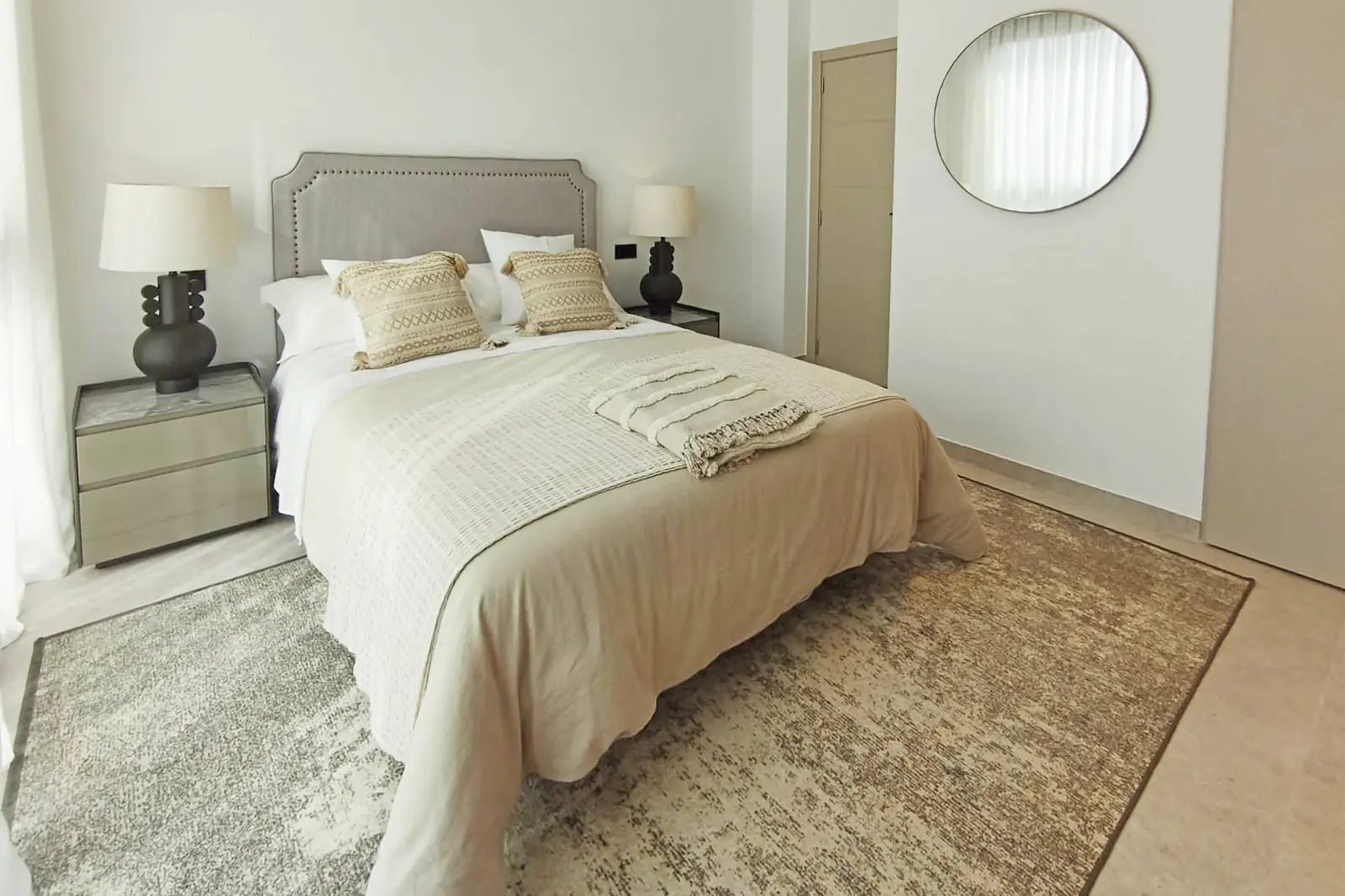 A stylish bedroom with a large bed and decorative mirror in a 4-bedroom villa in La Nucia - The Estates