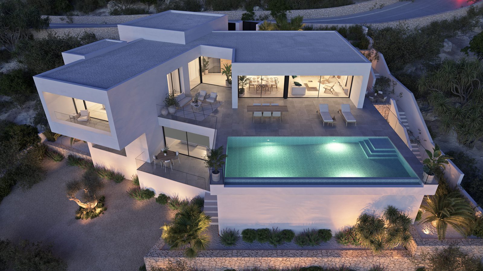 Aerial view of a modern 3-bedroom villa with illuminated pool, terraces and landscaped grounds in Benitachell - The Estates