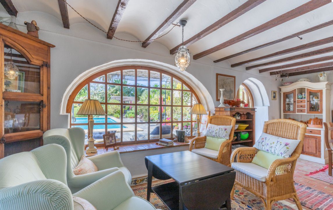 A bright living room with arched windows overlooking a pool in an 8-bedroom finca in Moraira - The Estates