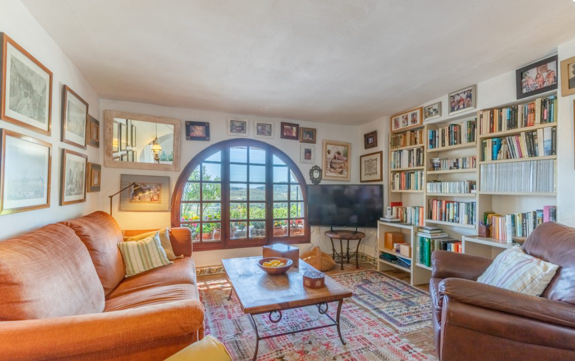 A cozy living room with a large arched window overlooking the countryside of an 8-bedroom finca in Moraira - The Estates