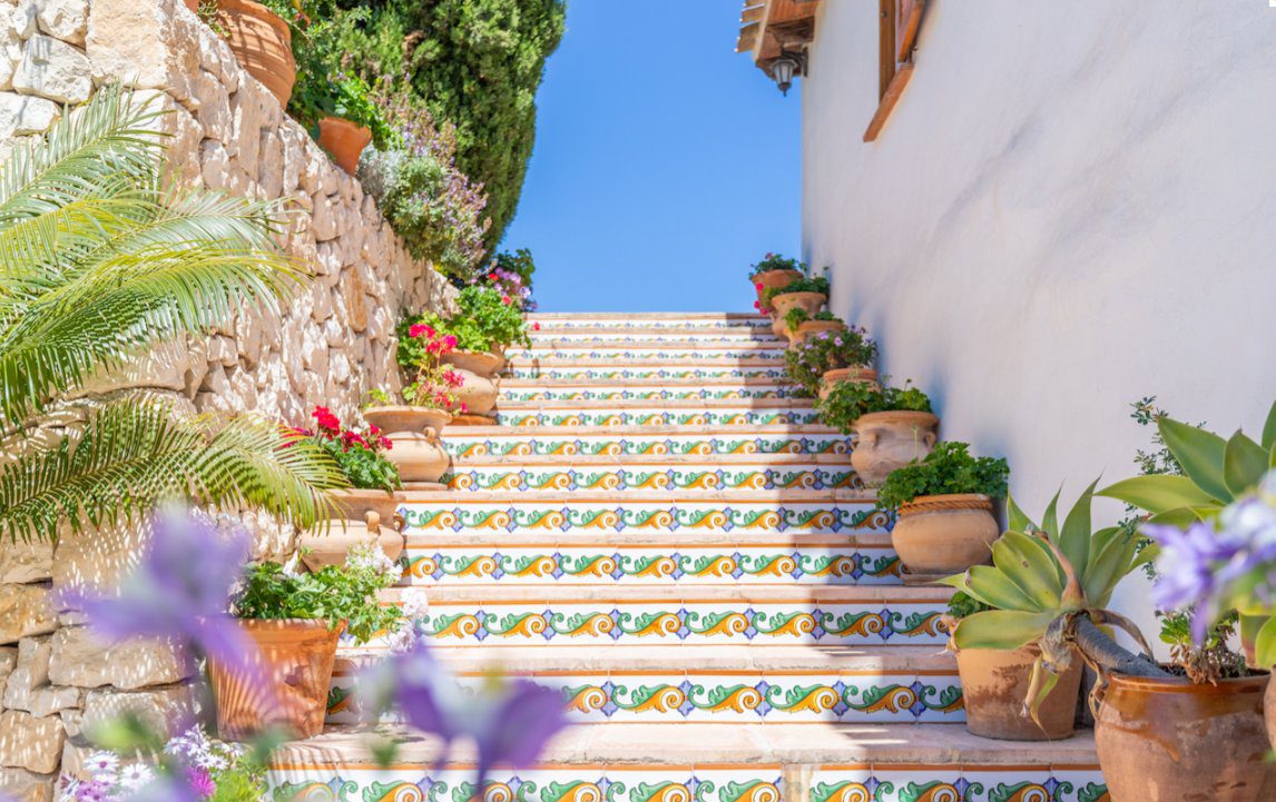Colorful tiled steps and lush greenery adorn the exterior of an 8-bedroom finca in Moraira - The Estates