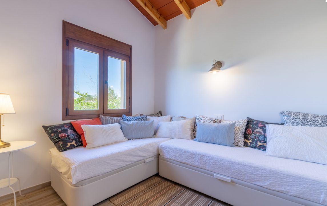 Bright bedroom with a corner sofa bed and window overlooking countryside in an 8-bedroom finca in Moraira - The Estates