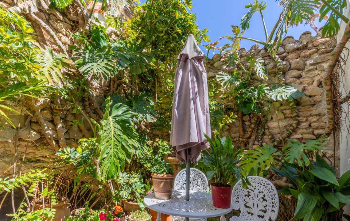 A charming outdoor seating area with lush greenery and a parasol at an 8-bedroom finca in Moraira - The Estates