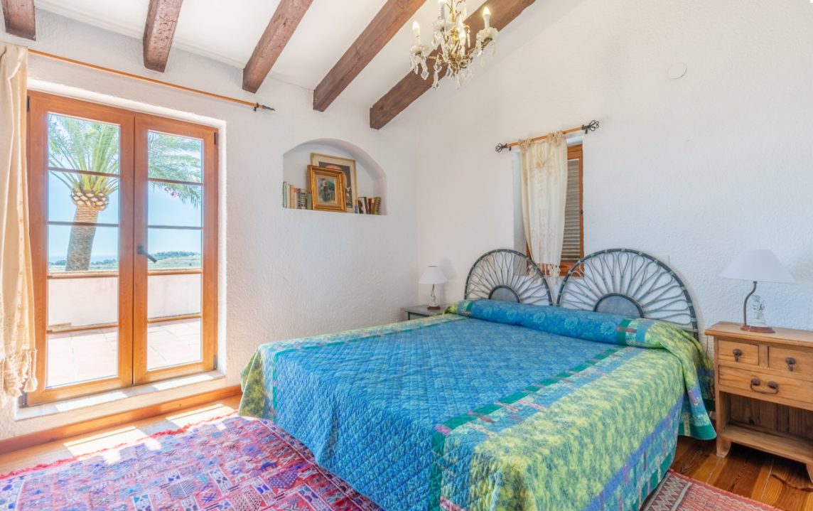 Elegant bedroom with exposed beams and sea views inside an 8-bedroom finca in Moraira - The Estates