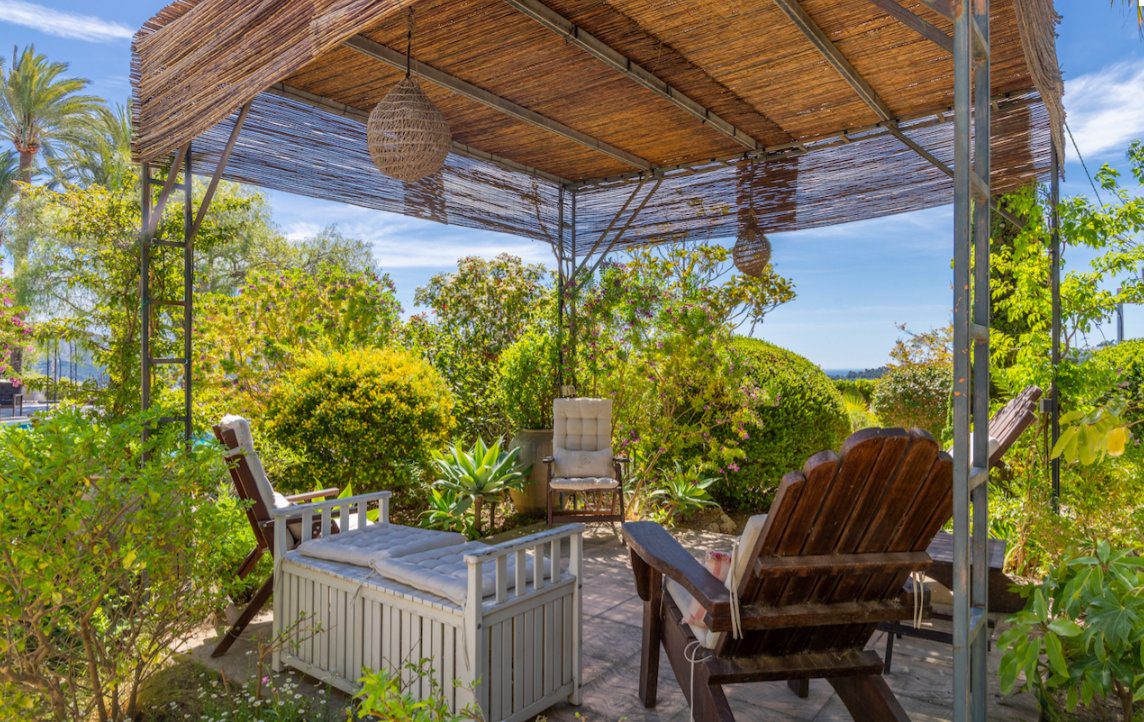 A relaxing shaded outdoor seating area with garden views at an 8-bedroom finca in Moraira - The Estates