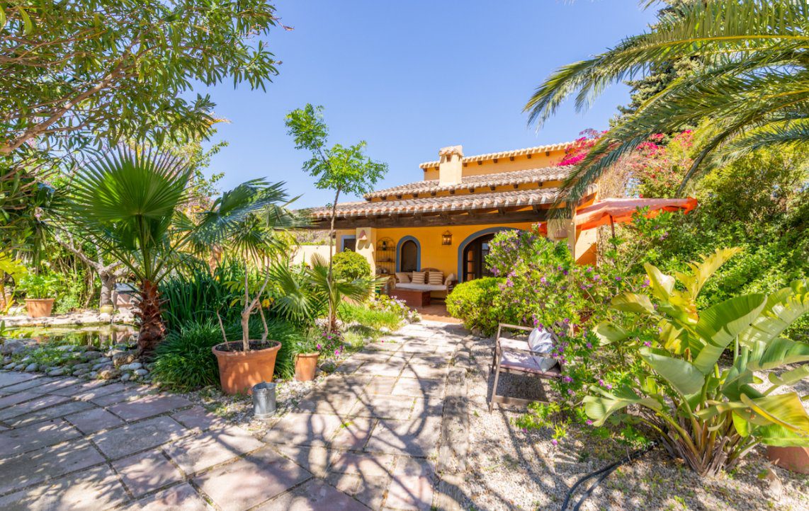 A beautiful outdoor seating area surrounded by lush tropical foliage of an 8-bedroom finca in Moraira - The Estates