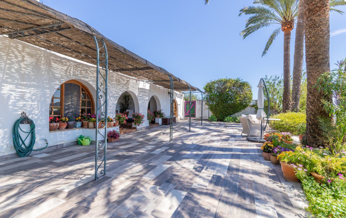 A beautiful outdoor terrace with lush greenery and palm trees at an 8-bedroom finca in Moraira - The Estates
