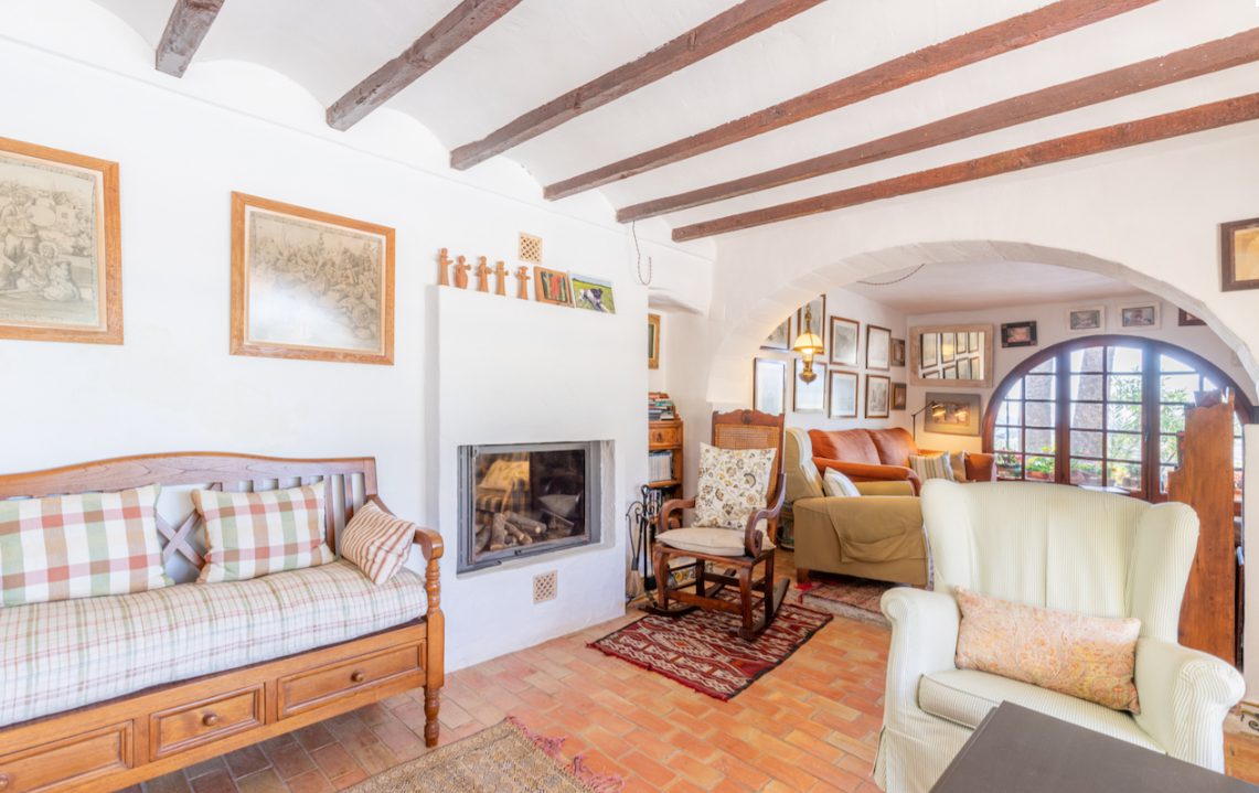 A cozy living room with exposed beams and a fireplace in an 8-bedroom finca in Moraira - The Estates