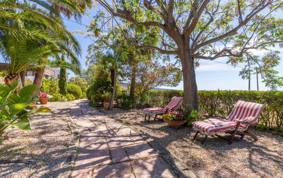 Lush garden with lounge chairs and sea views at an 8-bedroom finca in Moraira - The Estates