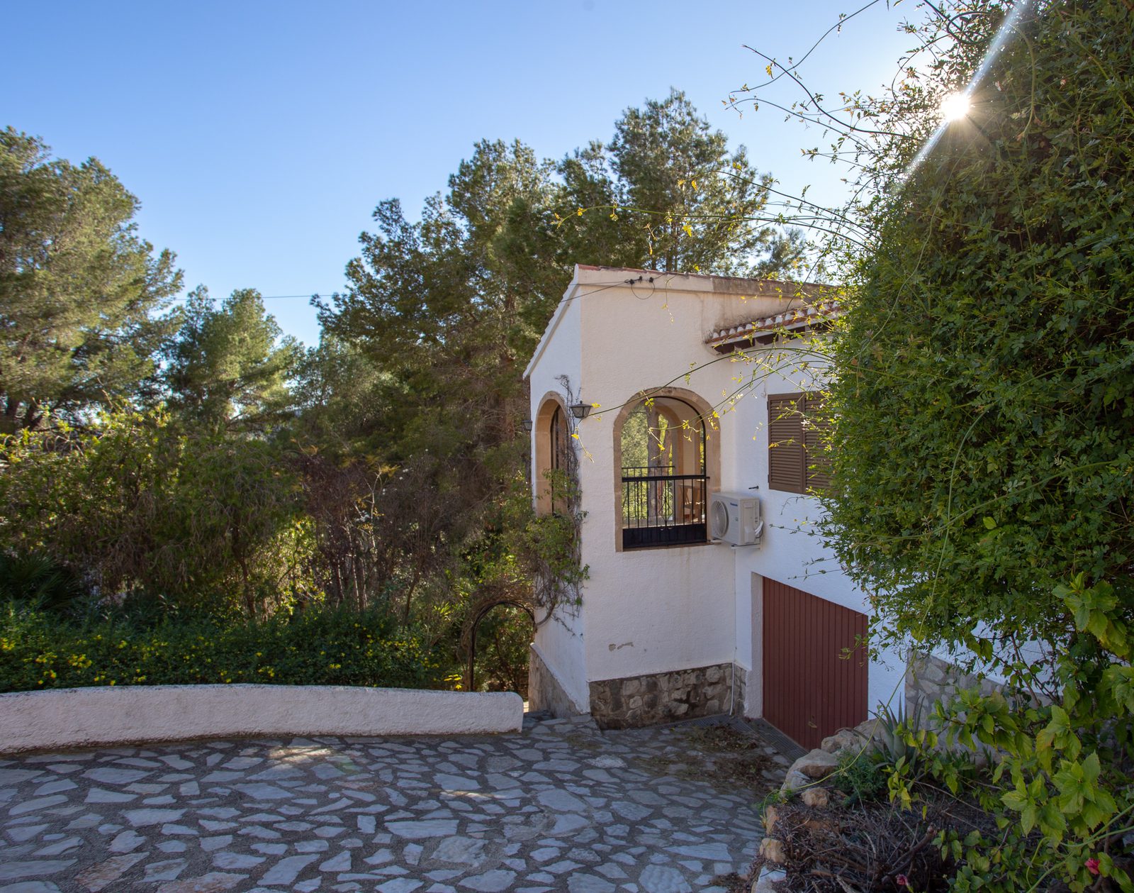 A charming villa exterior with lush greenery and a stone pathway in Javea / Xabia - The Estates