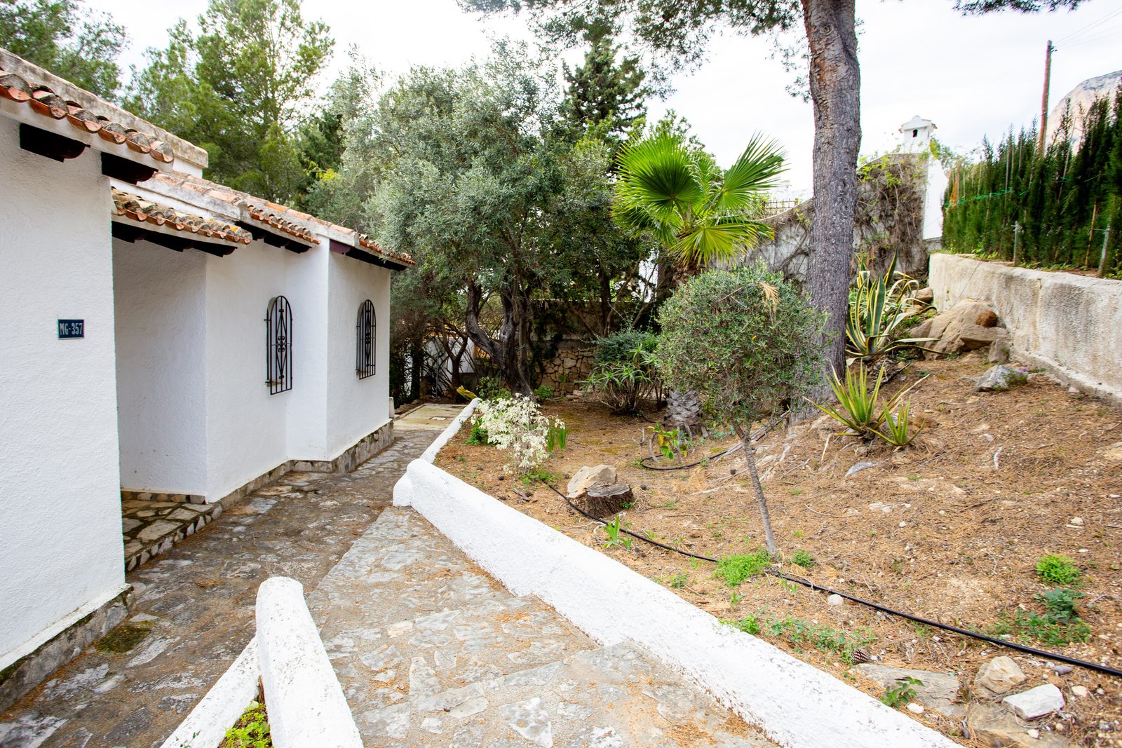 Exterior view of a charming 2-bedroom villa nestled amongst lush greenery in Javea / Xabia - The Estates