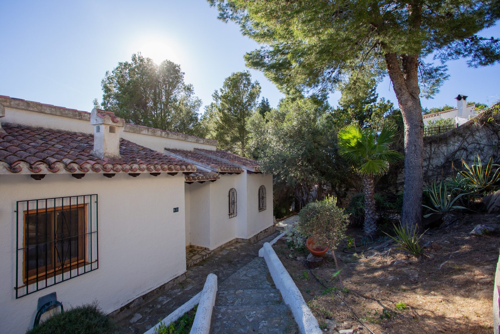 Exterior view of a charming 2-bedroom villa nestled amongst lush greenery in Javea / Xabia - The Estates