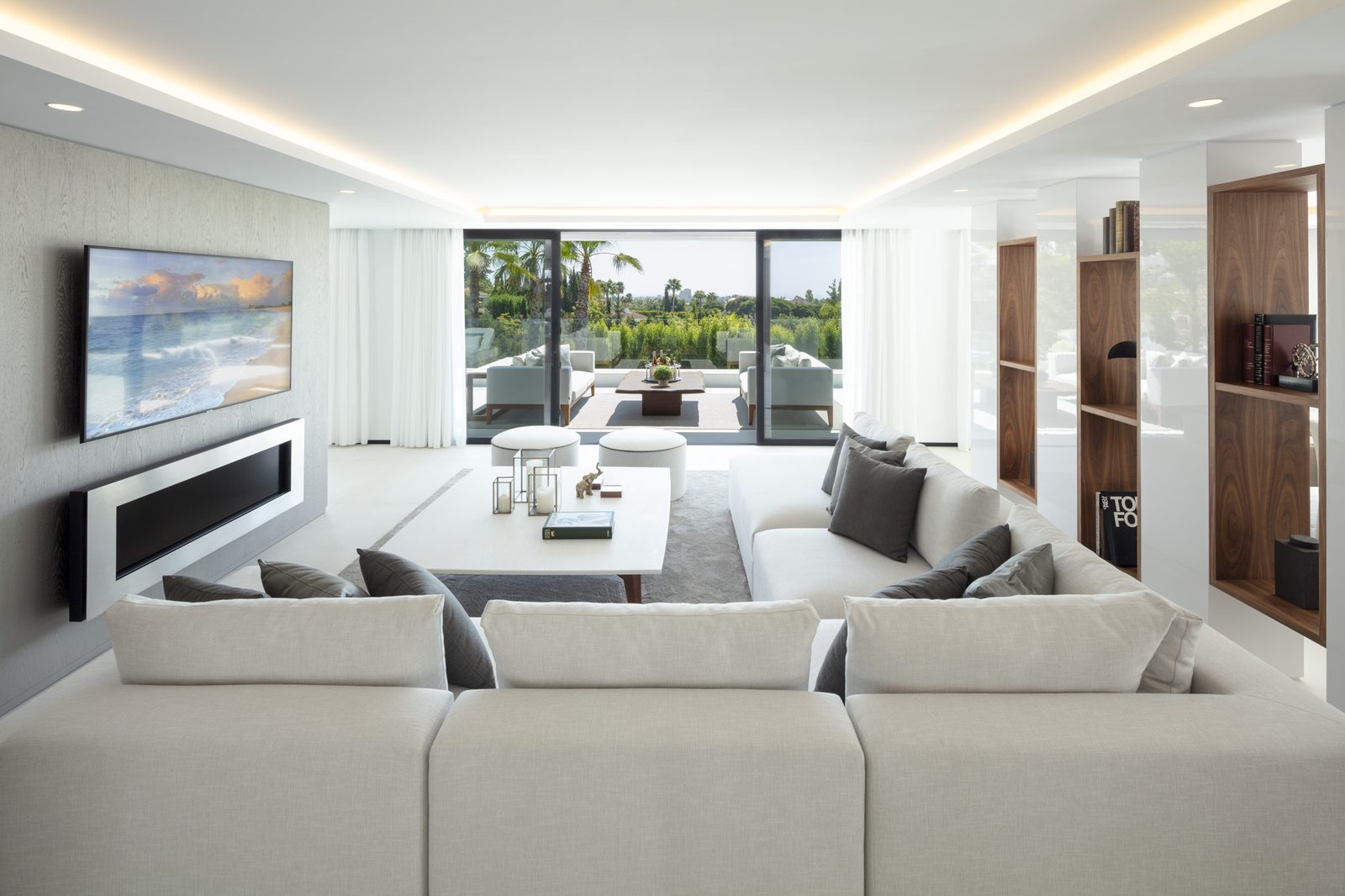 Contemporary living room with wall-mounted TV, designer seating and garden views in a 5-bedroom villa in Málaga - The Estates