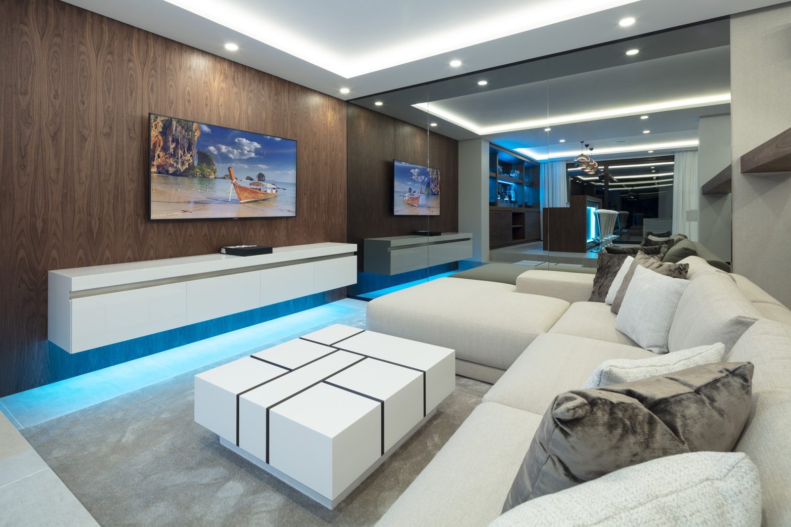 Modern living room with sectional sofa, wood-panelled wall, television and blue ambient lighting in a 5-bedroom villa in Málaga - The Estates
